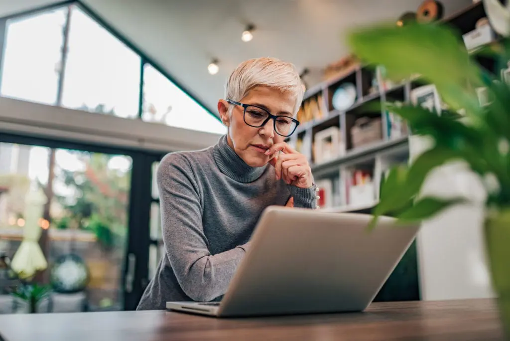 Portrait of a serious senior woman looking at laptop, used by AvidXchange for article explaining how accounts payable automation benefits security