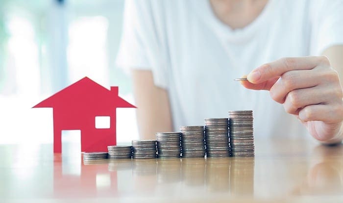 stack of coins next to paper cut out of house