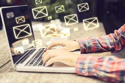 casually dressed male typing on laptop with floating email graphics