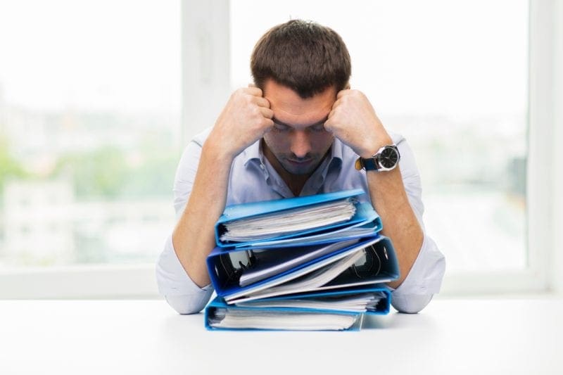 frustrated business professional sitting with stack of binders