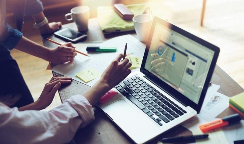 business people huddled around desk with laptop