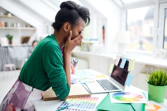 professional woman sitting at desk with face in hands