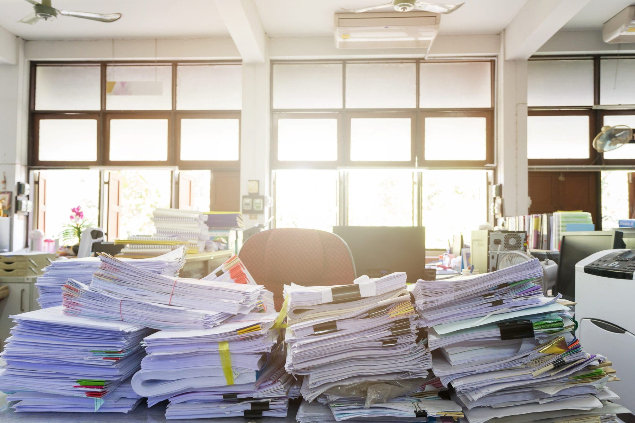 multiple large stacks of paper on a desk