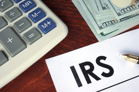 calculator money and IRS paperwork on table