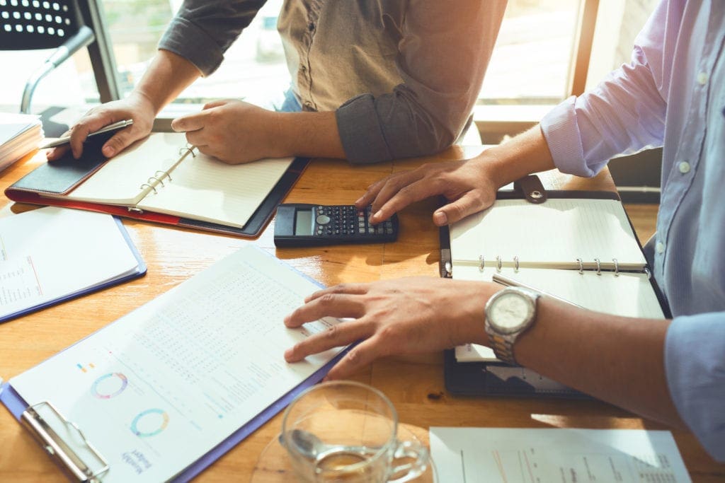 hands on files sitting on conference table