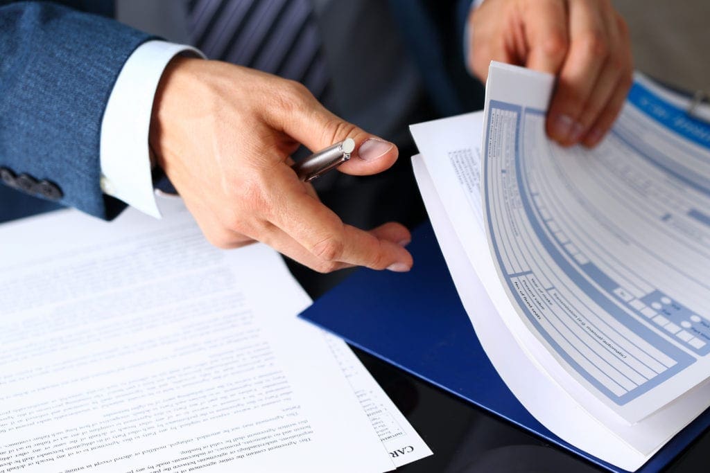 man in suit flipping through file papers