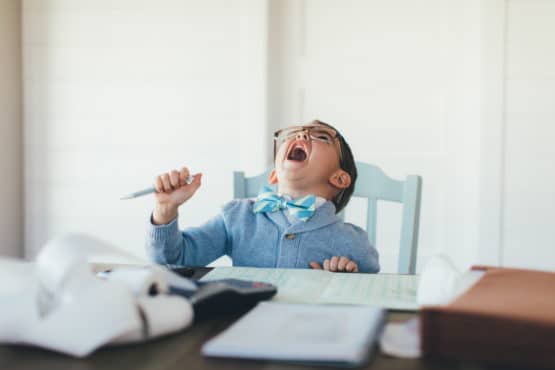 young boy in business suit sitting at desk laughing