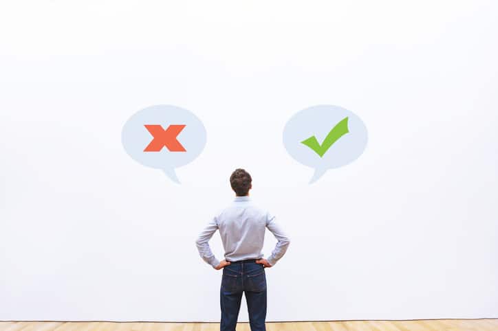 man-standing-in-front-of-wall-with-x-and-check