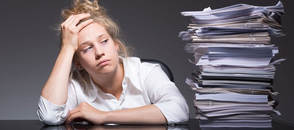 young woman stares at pile of paper