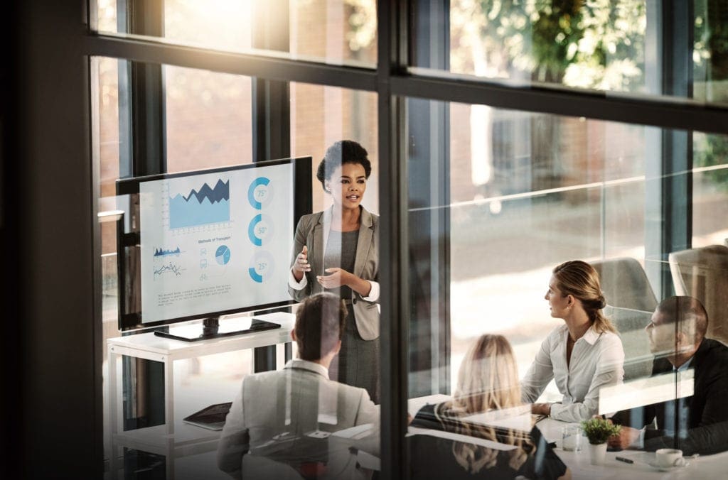 Shot of a businesswoman delivering a presentation to her colleagues in the boardroom, used by AvidXchange for article about financial planning to get your business back on-track during COVID-19