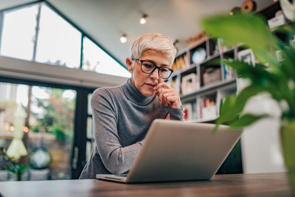 Portrait of a serious senior woman looking at laptop, used by AvidXchange for article explaining how accounts payable automation benefits security