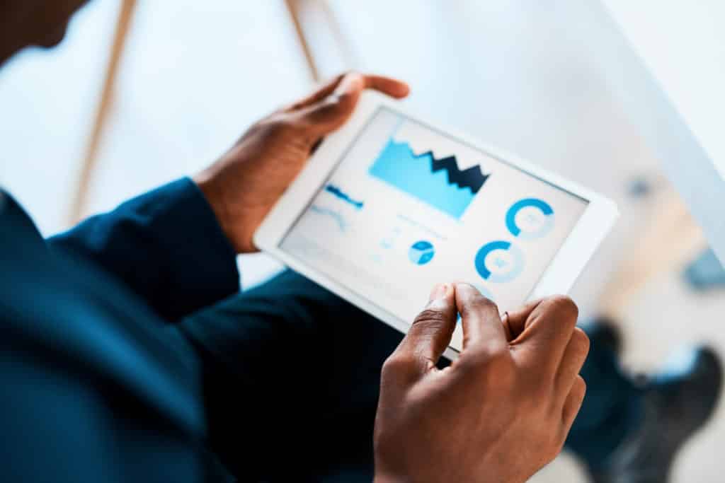 Man sitting looking at data on a tablet.