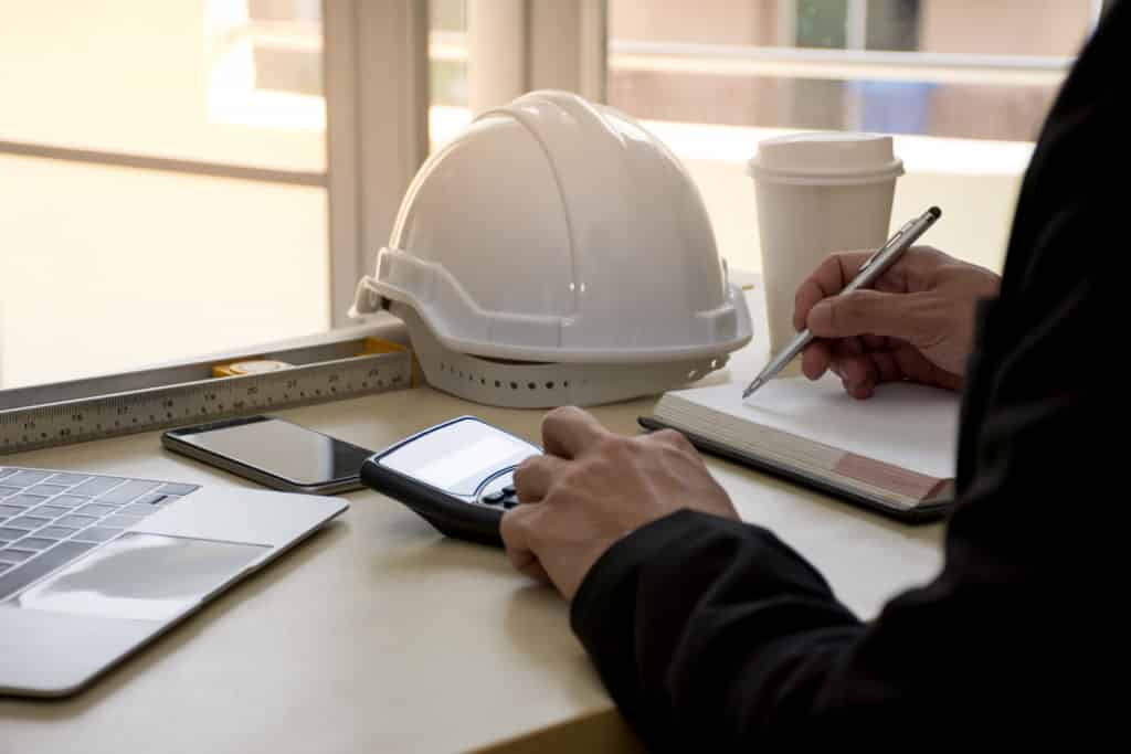 Close up of civil design engineer is making structural analysis calculations using a scientific calculator with laptop computer.