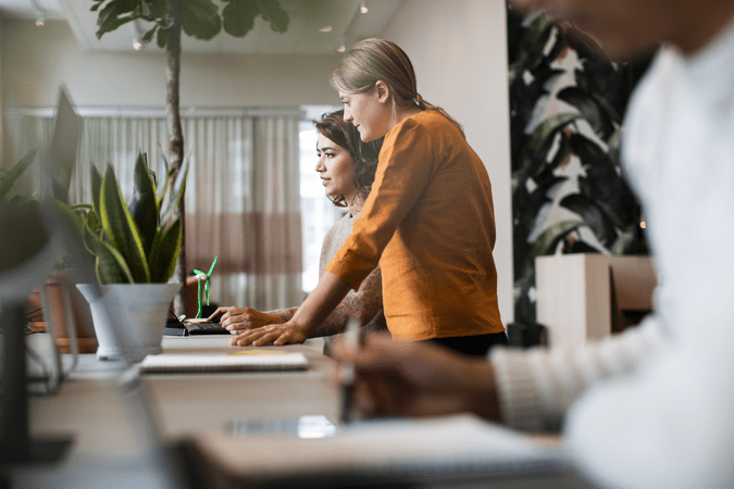 two women working together at computer desk