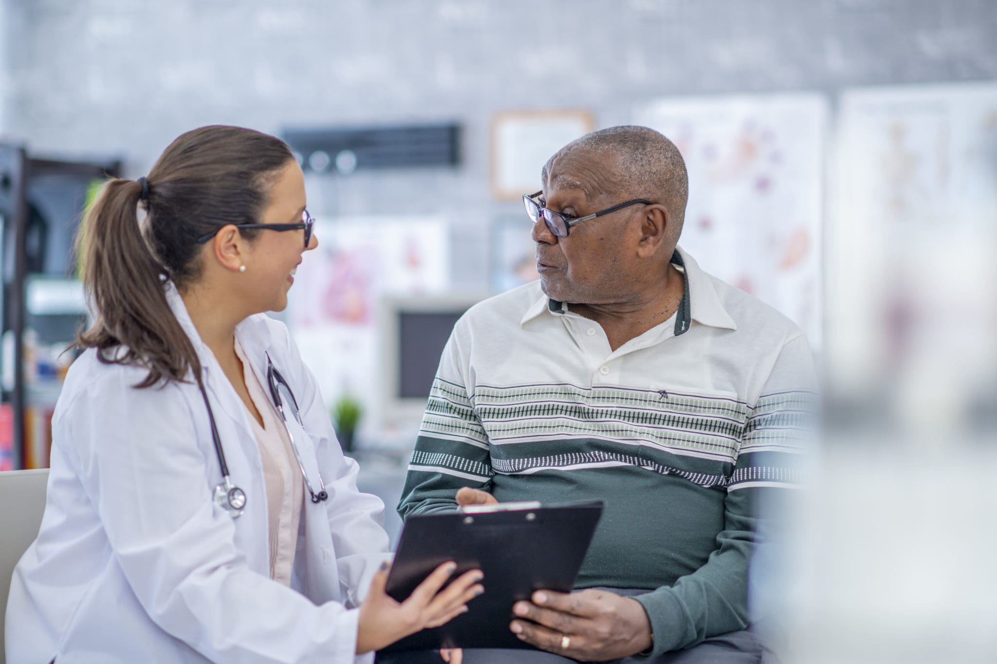 Older man discusses medical chart with female doctor