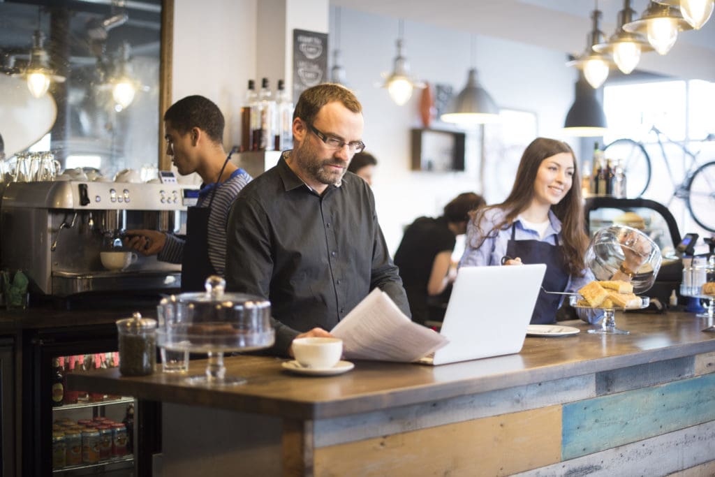 A business owner checks his bills against his online bank account