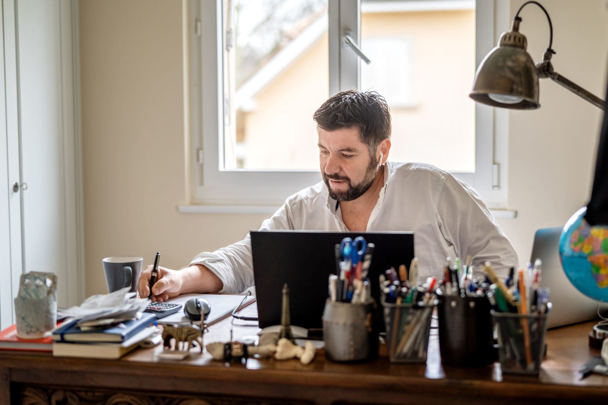 Man with earphones having conference call online sitting at home office with laptop.