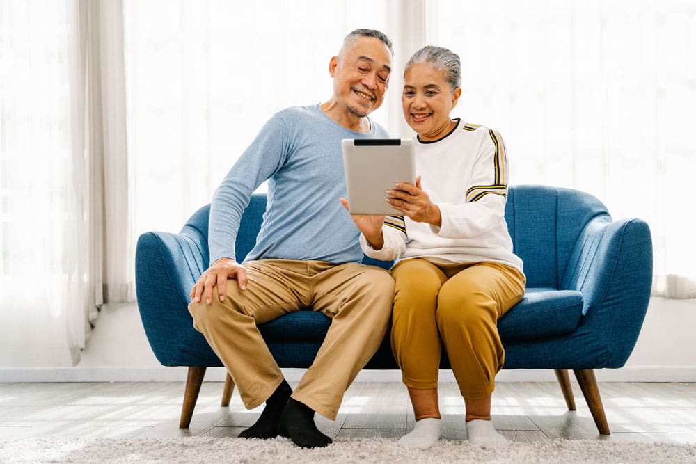 Man and woman sitting on a couch looking at tablet.
