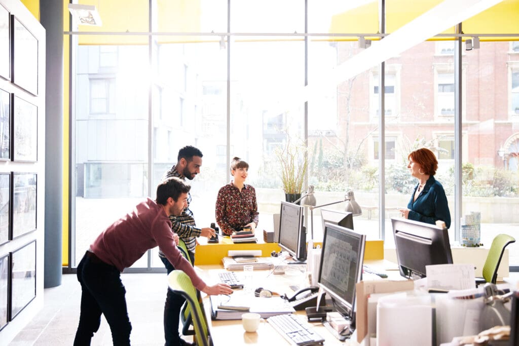 Coworkers talking over ideas in open plan office