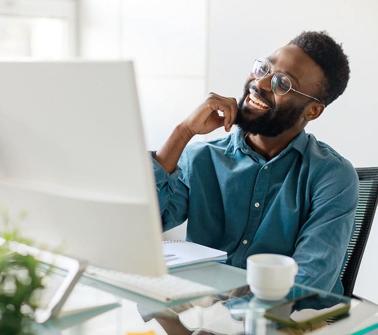 Happy black male manager sitting at office desk