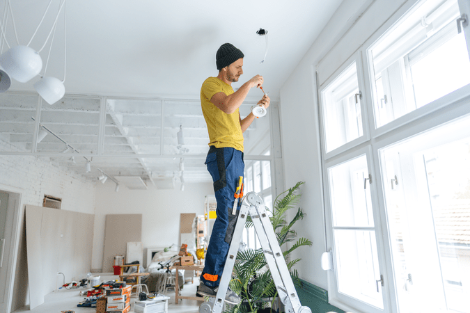 man on ladder changing light bulb