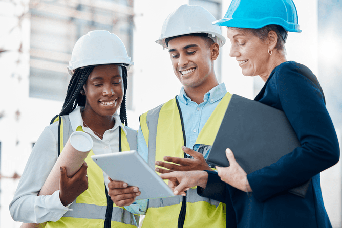 Construction workers with hard hats looking at a tablet