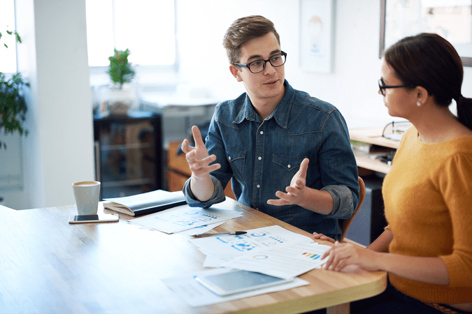 man and woman talking at a desk in a meeting