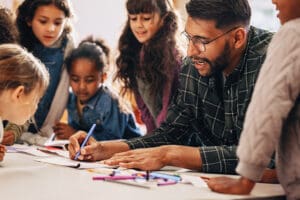 Man teaches his students how to draw in a primary school class