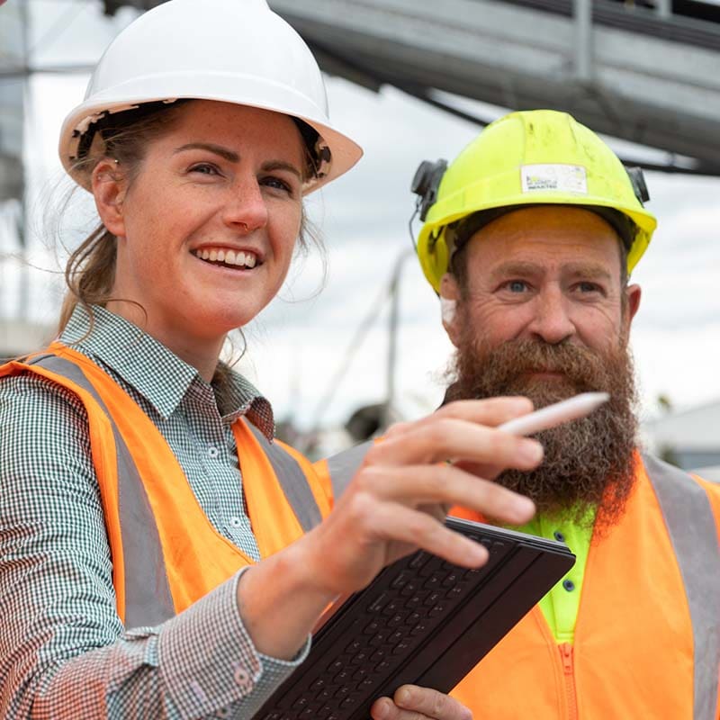 Female construction foreman speaking with co-worker on site.