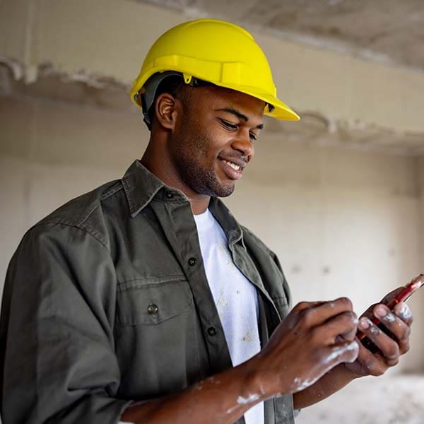 Construction worker looking at his phone and smiling.