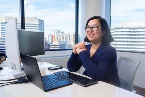 Ella Hu sitting at her desk smiling.