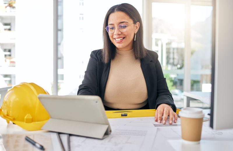 Real estate developer tracking job costs on property development using tablet at her desk