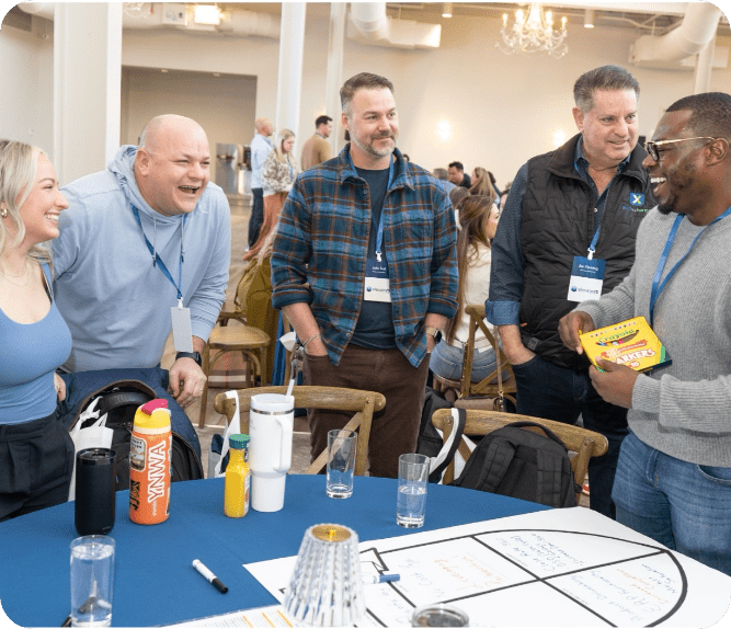AvidXchange employees gathered around a table laughing.