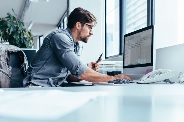 Real estate professional looking at computer monitor while working in office.