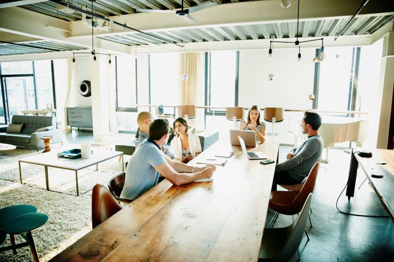 Business colleagues discussing project at conference room table in office coworking space