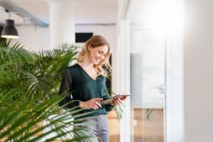 Woman smiling at tablet in bright office setting