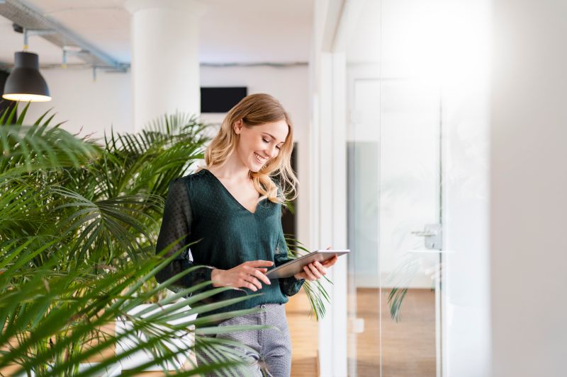 Woman smiling at tablet in bright office setting