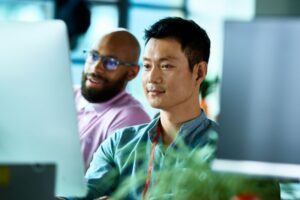 Two male co-workers looking at computer screen