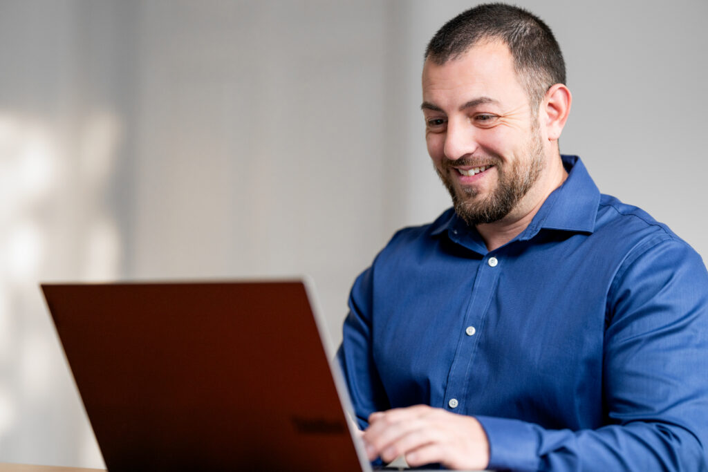 Nick Riso sits at a desk typing on a laptop