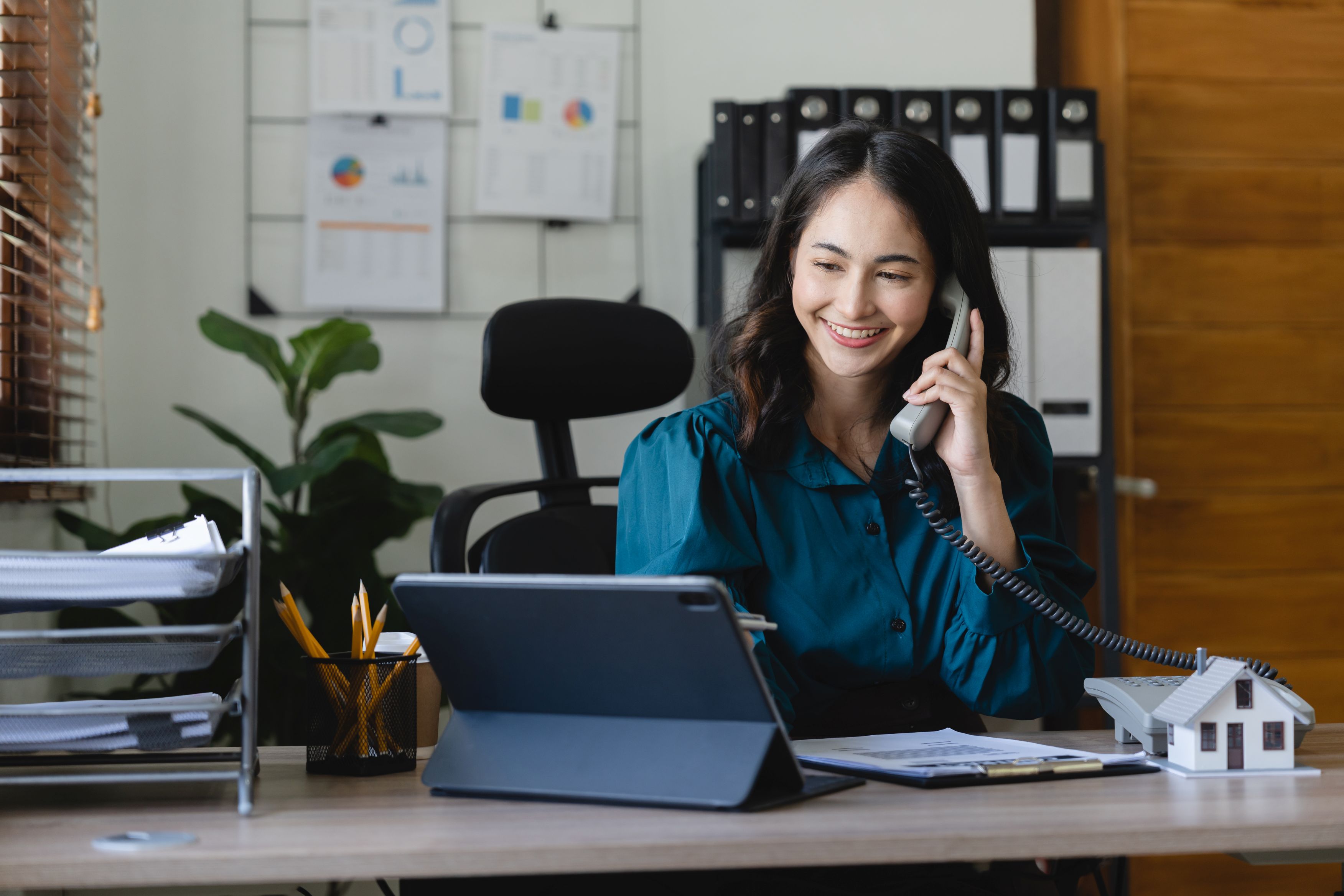 Community Association Manager on the phone at her desk while working on tablet