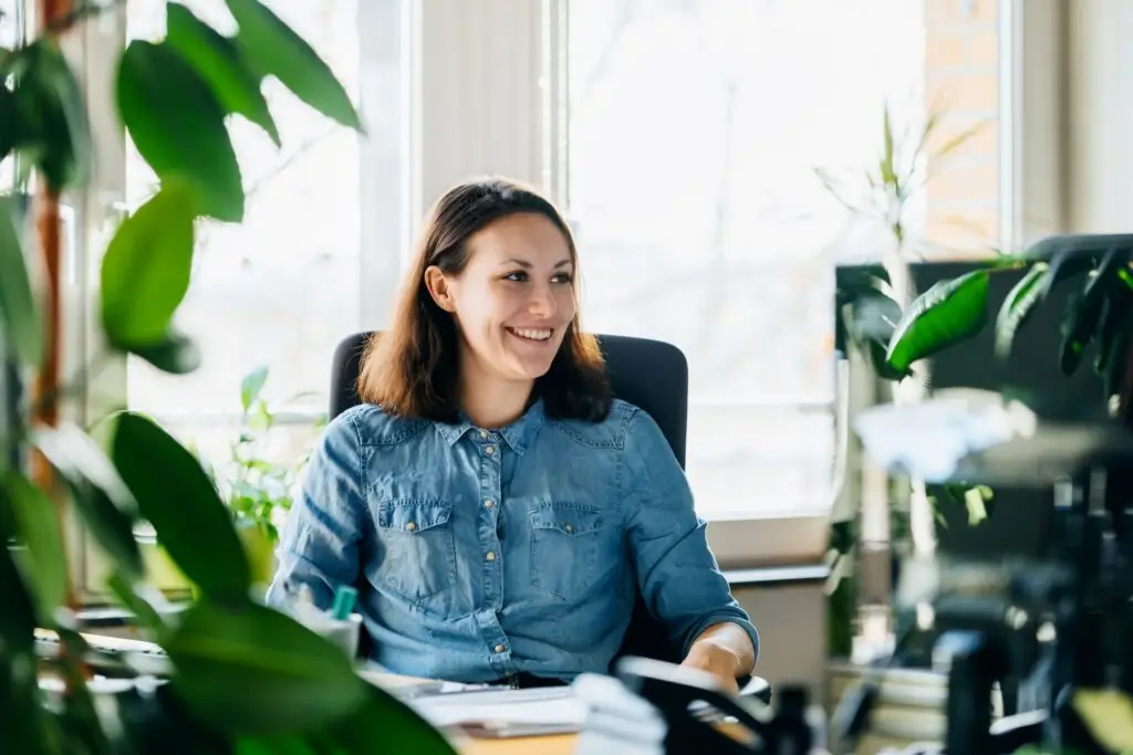Promotional image for blog about the cost of paper checks in community management featuring a woman working in a modern office